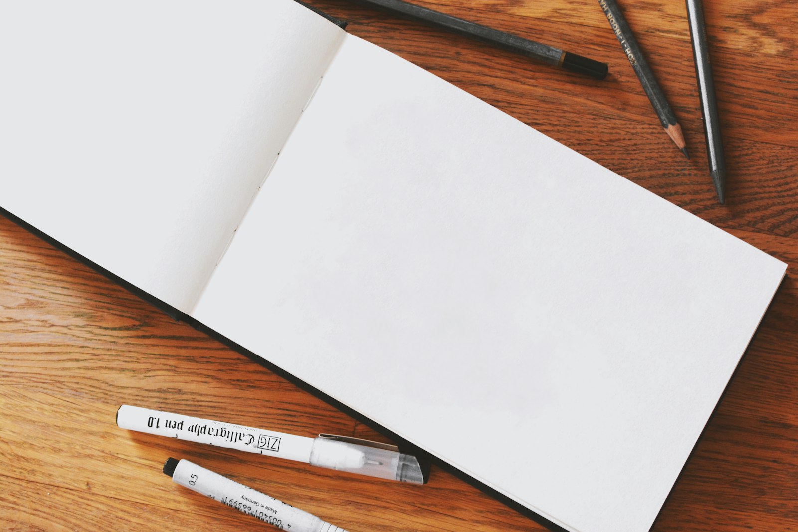 Cuaderno de bocetos con lápices sobre escritorio de madera